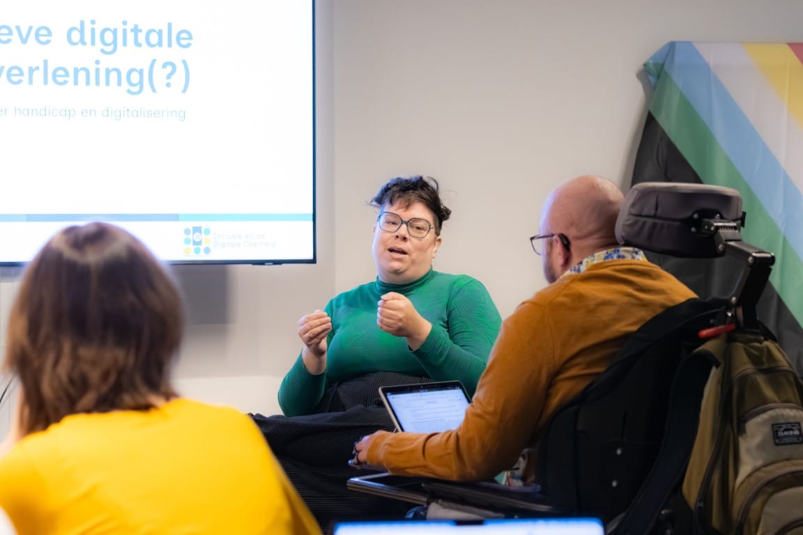Foto van de lancering, Maranke is tussen deelnemers door te zien voor een scherm. Die is een wit persoon zittend in een rolstoel en praat met diens handen iets uitbeeldend. Op het scherm achter hen staat de powerpoint van de presentatie.